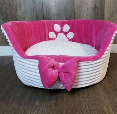 a dog bed with a pink bow tie and a pink bow